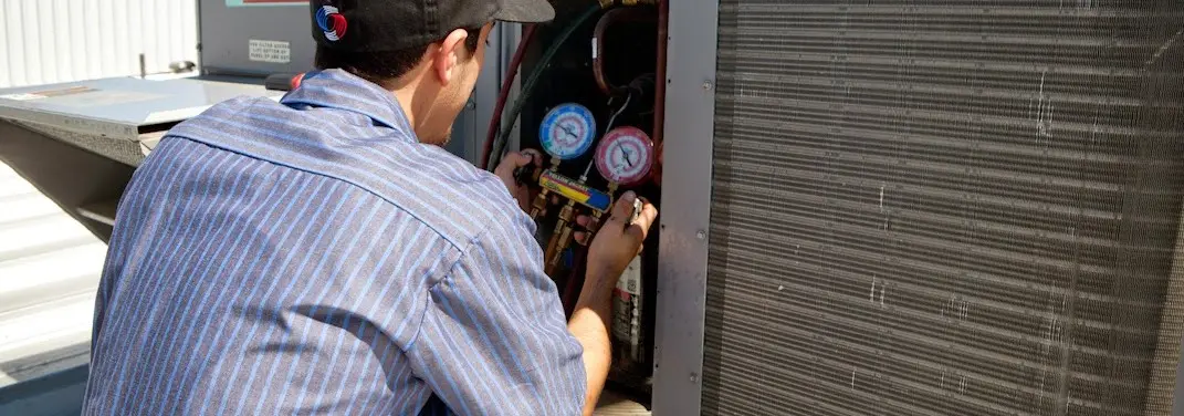 HVAC technician servicing a condenser unit in Exeter