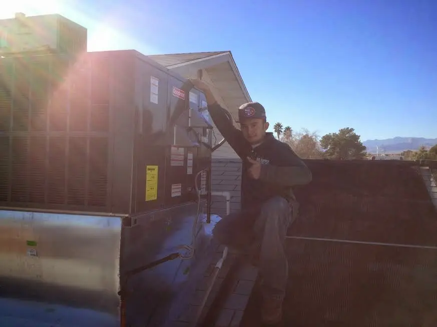 HVAC technician performing Air Duct Cleaning on a rooftop unit in Exeter